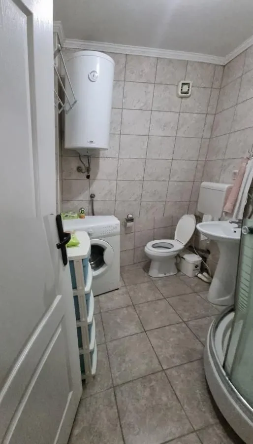 Kupatilo opremljeno tuš kabinom, WC šoljom, umivaonikom i mašinom za veš.