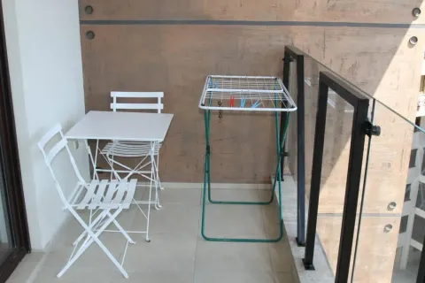 Small furnished balcony with a table, chairs, and a clothes drying rack. - image 6