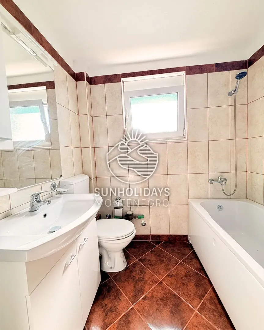 Small bathroom with a sink, toilet, bathtub, and window.