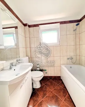 Small bathroom with a sink, toilet, bathtub, and window. - image 9