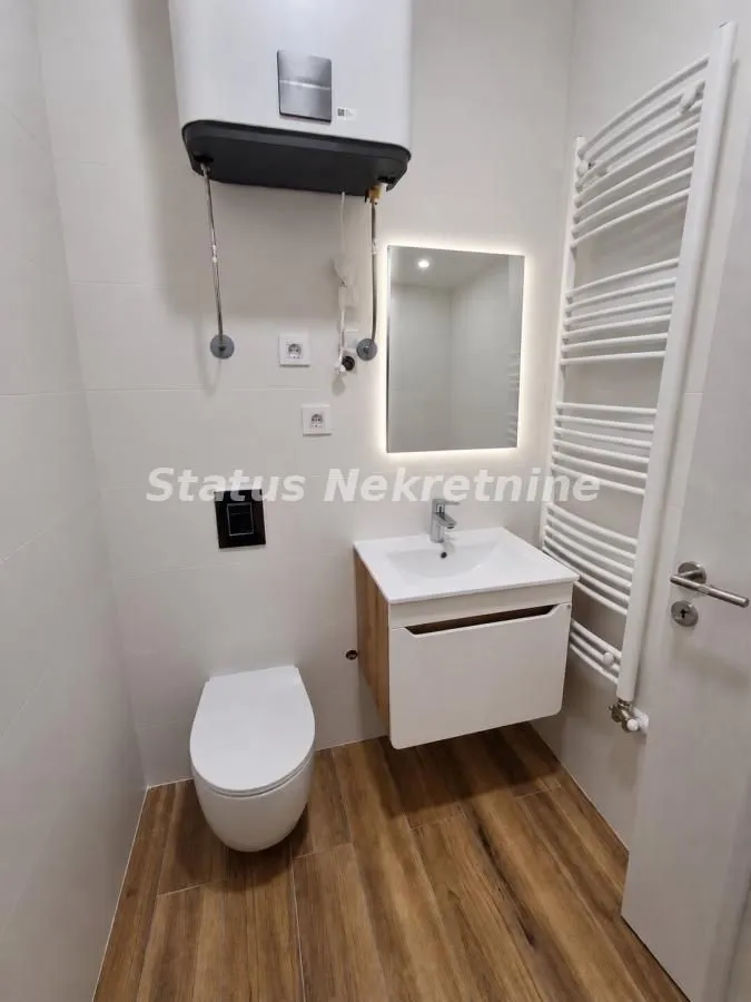 Smaller bathroom with a toilet, washbasin, and built-in water heater.
