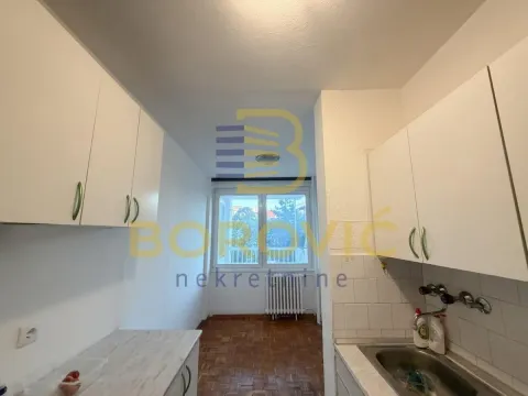 Manja kuhinja sa belim elementima i prozorom na kraju prostorije. - image 3