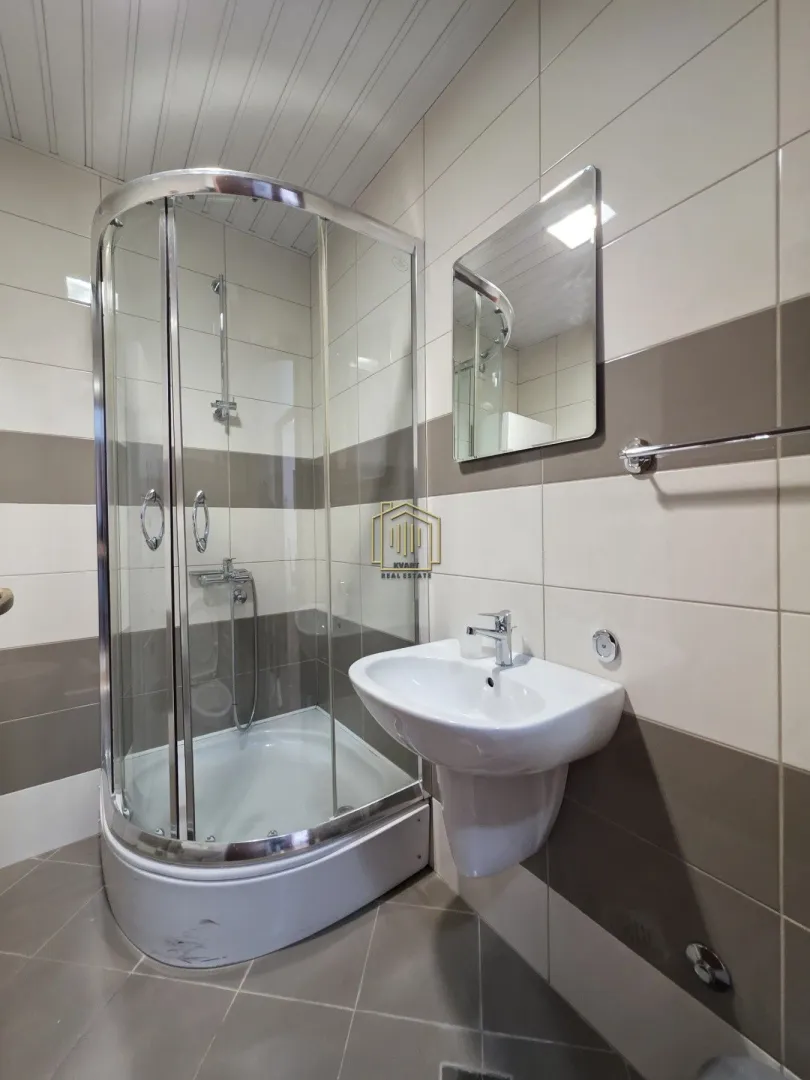 Bathroom with a shower cabin, washbasin, and mirror.