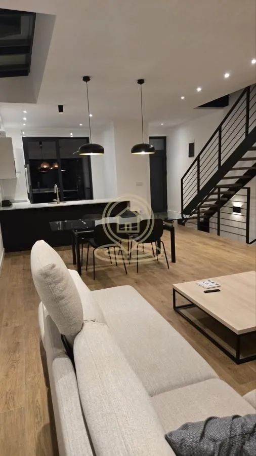 Spacious living room connected to the dining area and kitchen, featuring an interior staircase.