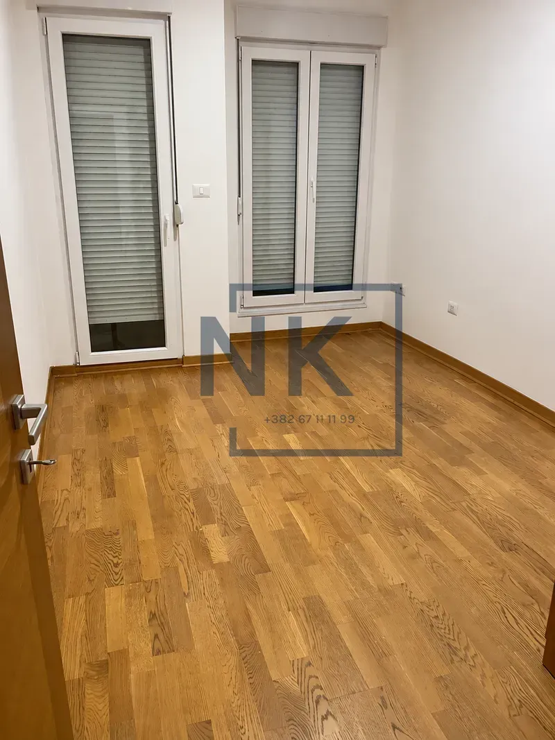 Empty room with parquet flooring and double doors leading to the terrace.