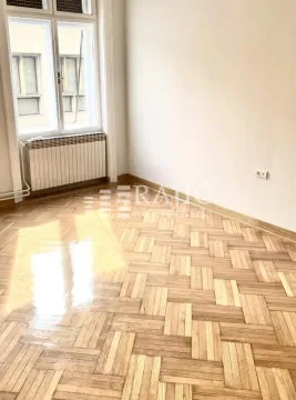 Empty room with parquet flooring and a large window. - image 11