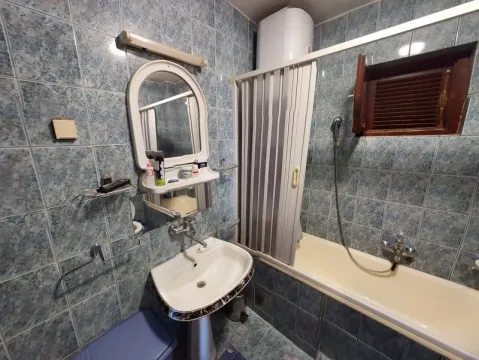 A bathroom with blue tiles, a bathtub, and a sink with a mirror. - image 8