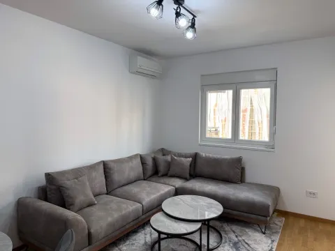 Living room with a grey sectional sofa, small round coffee tables, and an air conditioner. - image 6