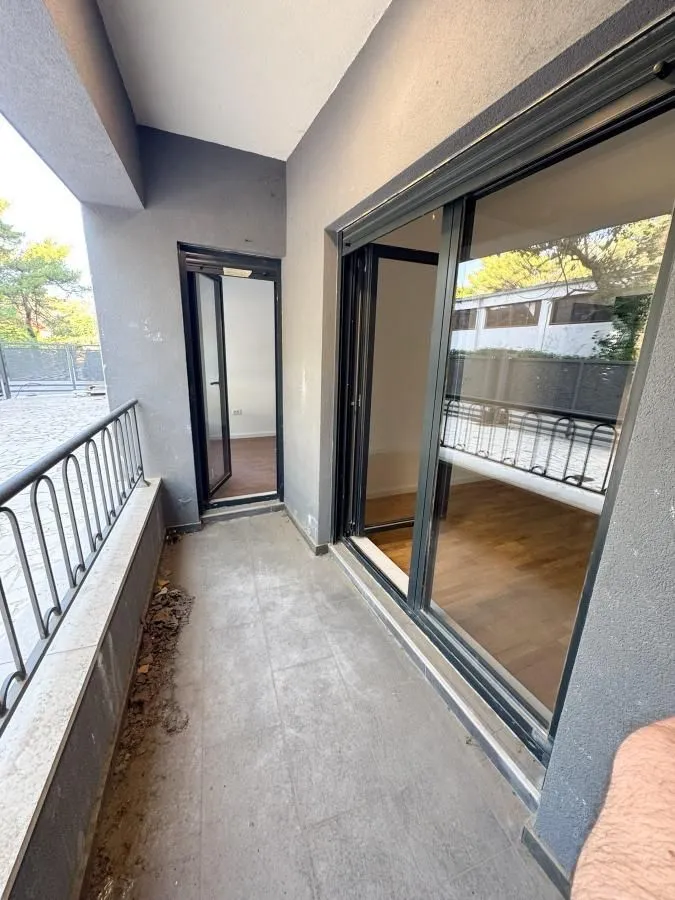 Nenamješten balkon sa staklenim kliznim vratima i metalnom ogradom.