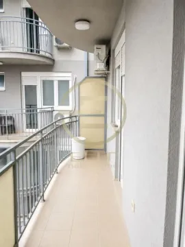 Dugačka popločana terasa sa metalnom ogradom i pogledom na unutrašnje dvorište zgrade. - image 10