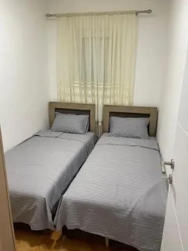 Bedroom with two single beds and a window with curtains. - image 3