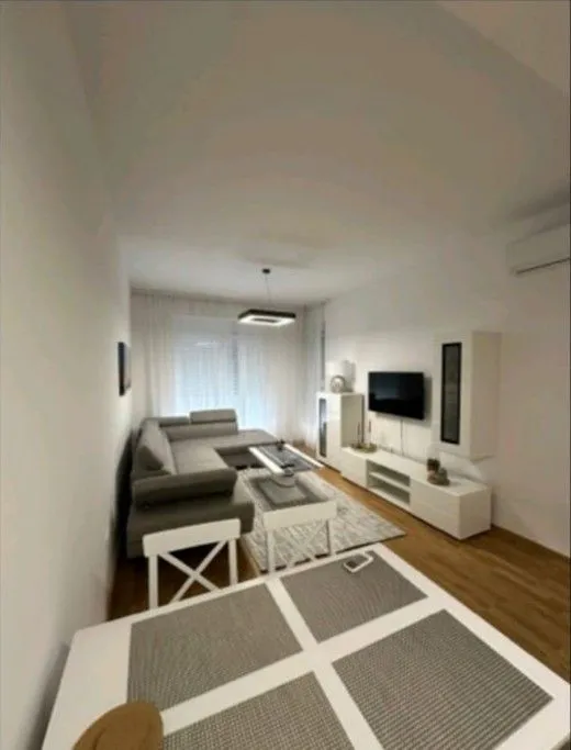 Living room with a sectional sofa, TV, and dining table in the foreground.