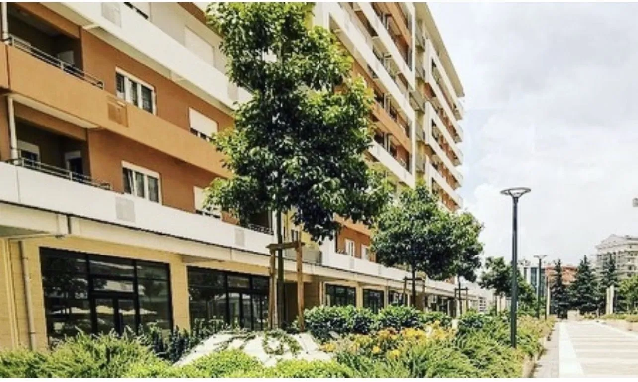 Exterior of a modern residential building with landscaped greenery in front.