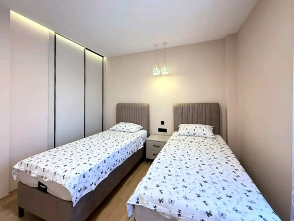Spavaća soba sa dva odvojena kreveta, ugradnim ormarom i noćnim stočićem.