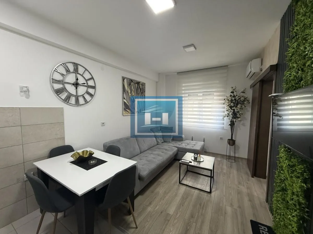 Living room with a sofa, dining table, and decorative wall.