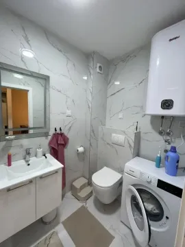 Modernly equipped bathroom with a washbasin, toilet, and washing machine. - image 7