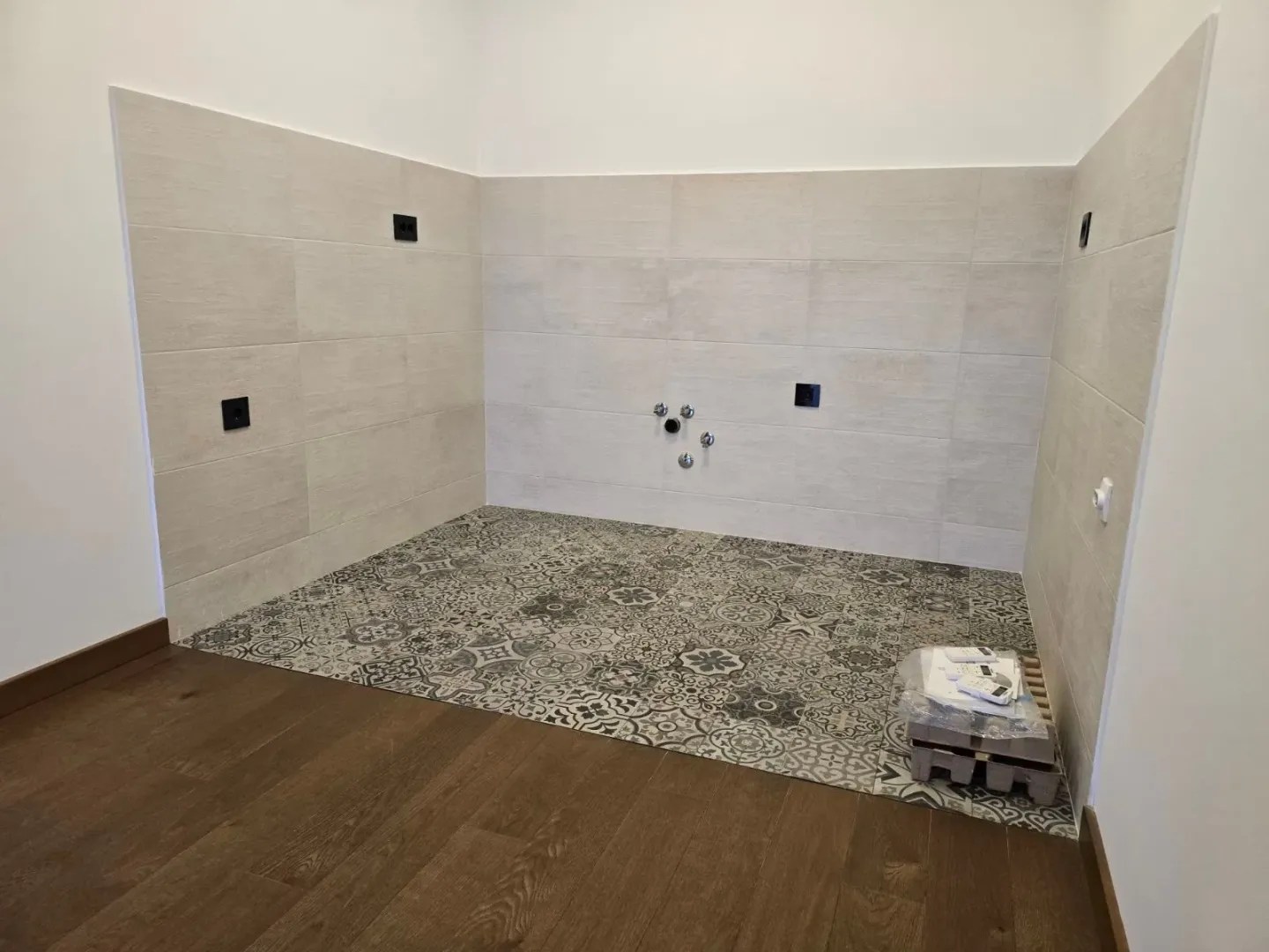 Part of the kitchen with ceramic tiles on the floor and walls and prepared connections.