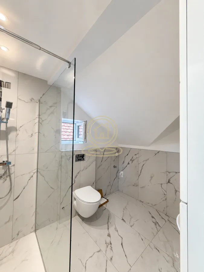 Modern bathroom with a walk-in shower and marble tiles.