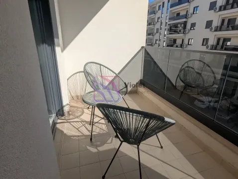 Small furnished balcony with two chairs and glass railing. - image 7