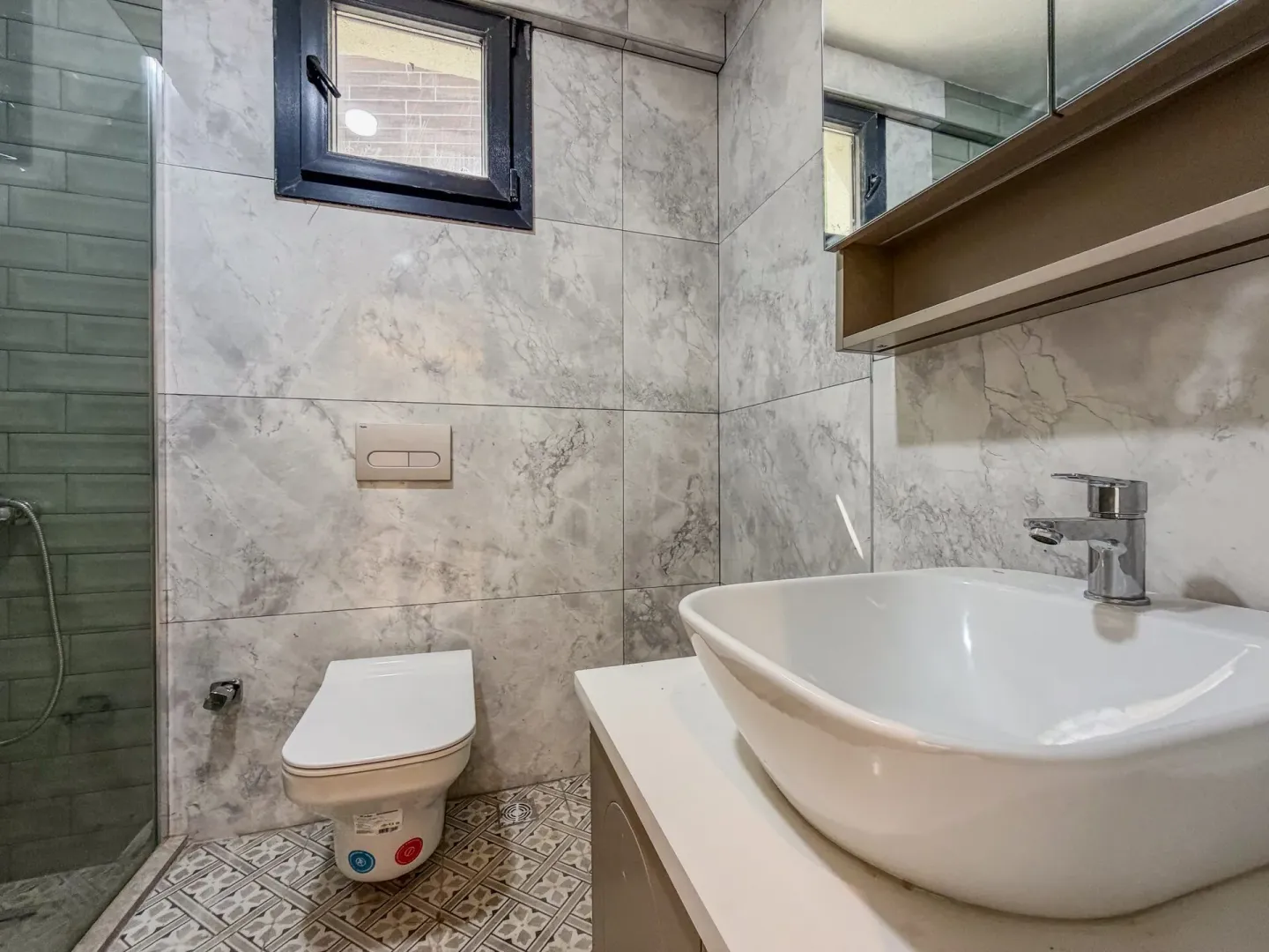 Moderne kupatilo opremljeno umivaonikom, WC šoljom i tuš kabinom sa staklenim paravanom.