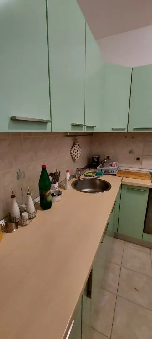 Kuhinja sa svijetlo zelenim elementima i bež radnom površinom.