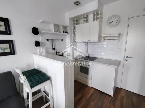 Small white kitchen with a breakfast bar and dining table. - image 9