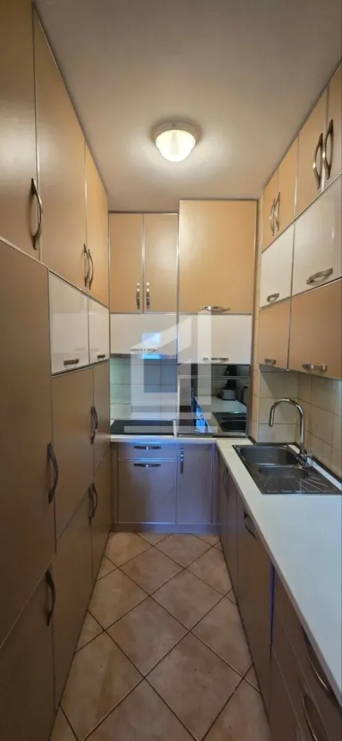 Compact kitchen with beige and white cabinetry and tiled flooring.