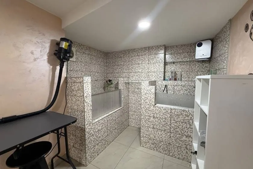 Tiled bathroom with a walk-in shower area and shelving units.