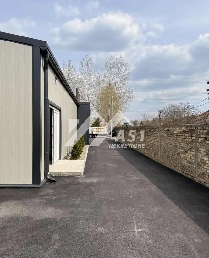 Asphalted yard and driveway next to the building with a fence.