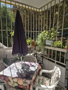 Natkriveni balkon sa stolom, suncobranom i ukrasnim biljem. - image 3