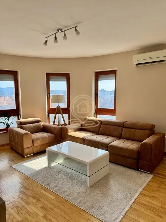 Living room with a sofa set, coffee table, and three windows with a view.