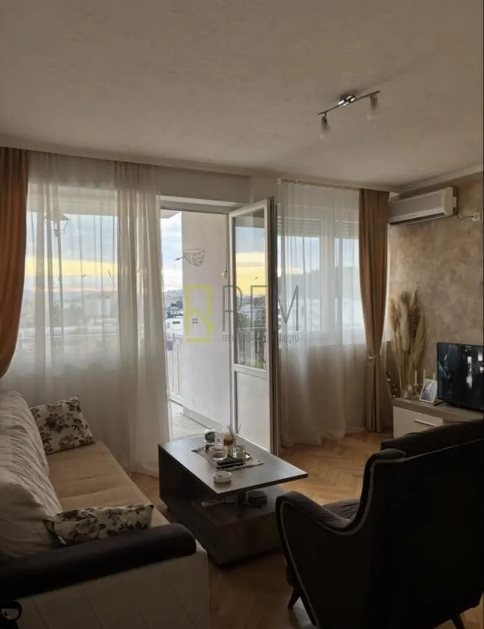 Dnevna soba sa garniturom, stočićem i izlazom na terasu.
