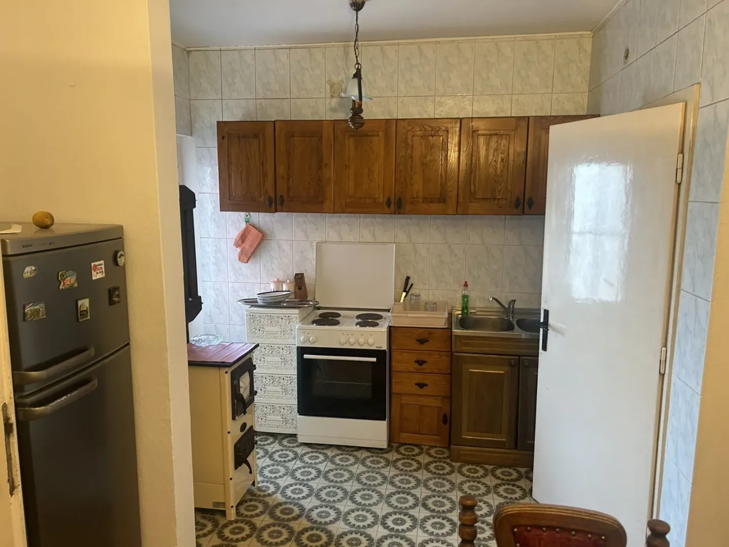 Classic kitchen with wooden cabinets, appliances, and patterned floor tiles.