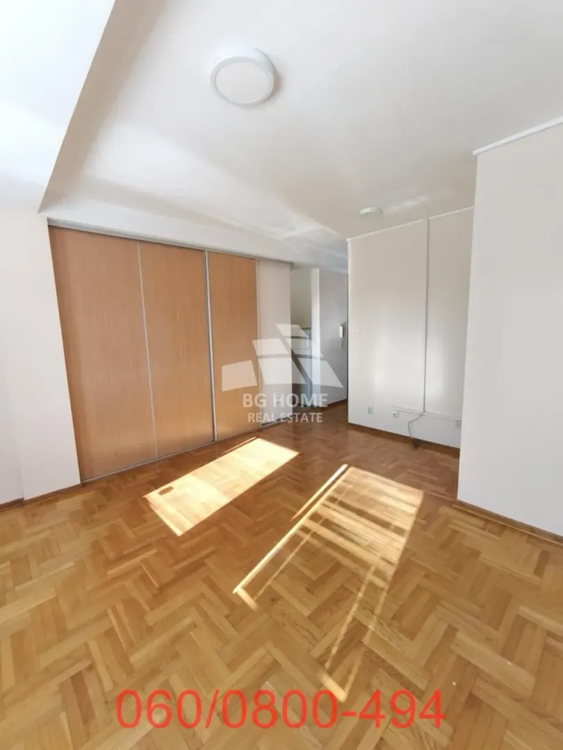 Empty bedroom with a built-in wardrobe and parquet flooring.