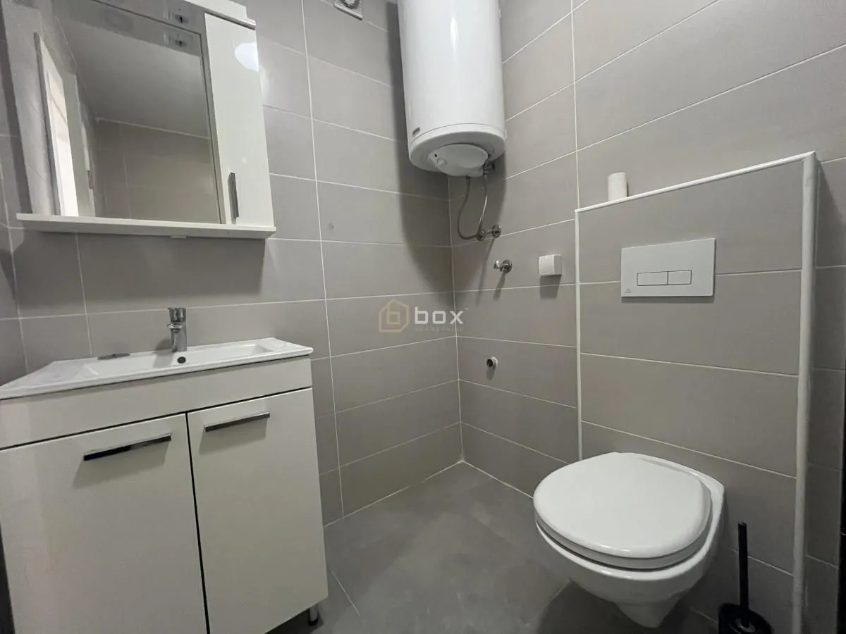 Small bathroom equipped with a washbasin, toilet, and water heater.