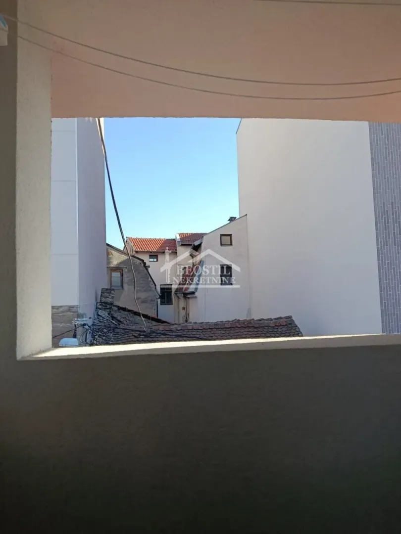 Pogled sa terase na susedne zgrade i krovove.