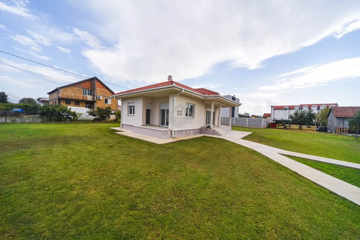 View of a ground-floor house with a spacious grassy yard and walkway.