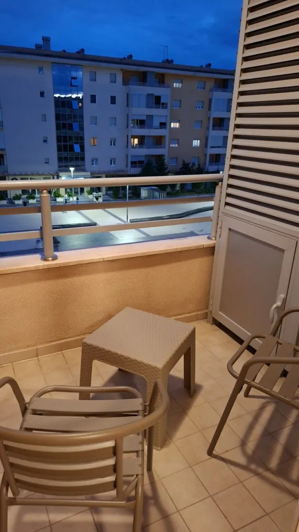 Manji namješteni balkon sa garniturom za sjedenje i pogledom na zgrade.