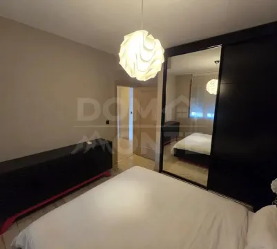 Uređena spavaća soba sa bračnim krevetom, garderoberom sa ogledalom i modernim lusterom. - image 6