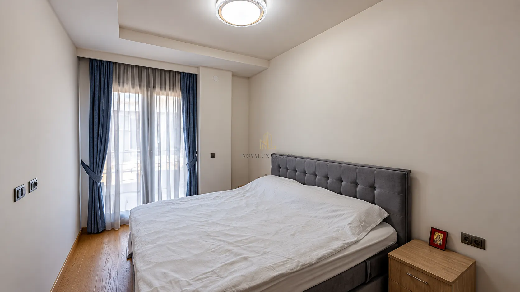 Spavaća soba sa bračnim krevetom i balkonskim vratima.