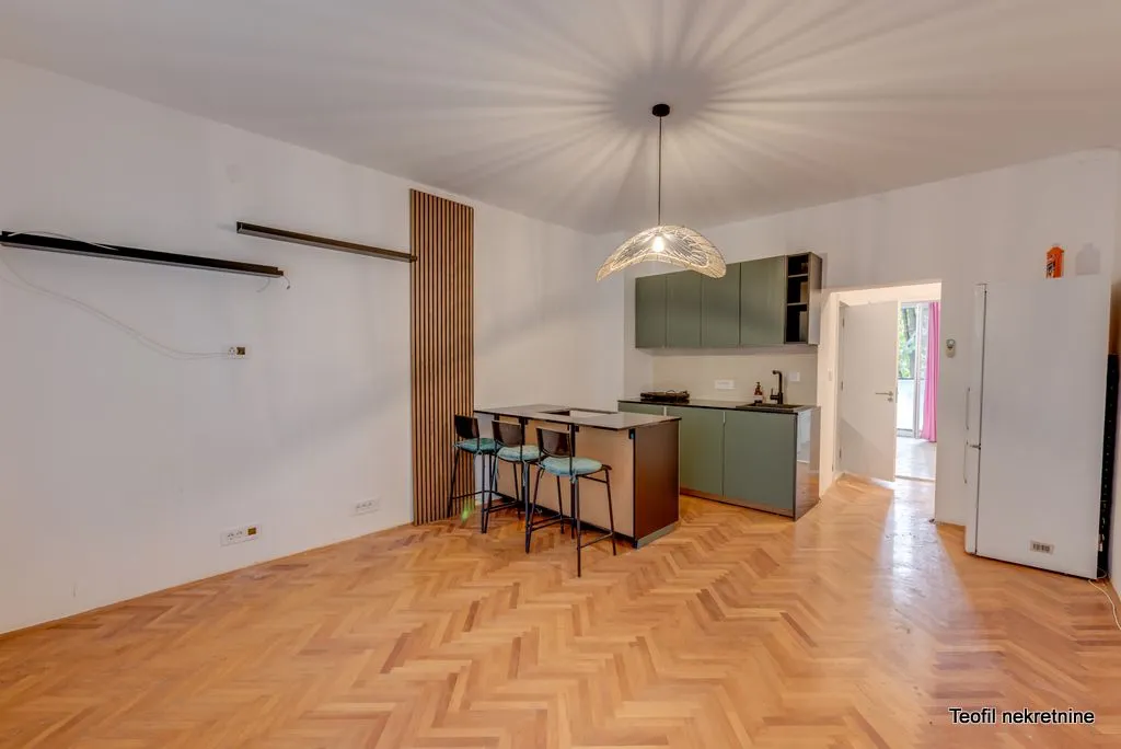 Modern kitchen with a bar counter and bar stools on hardwood flooring.