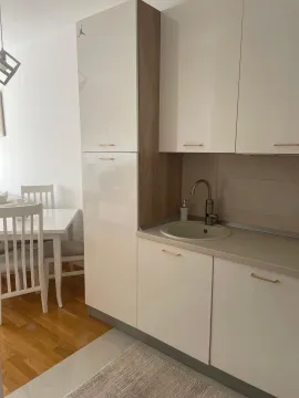 Manja moderna kuhinja sa sudoperom i bijelim elementima uz trpezarijski sto. - image 4