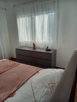 Bedroom with a double bed, chest of drawers, and a window with curtains. - image 6