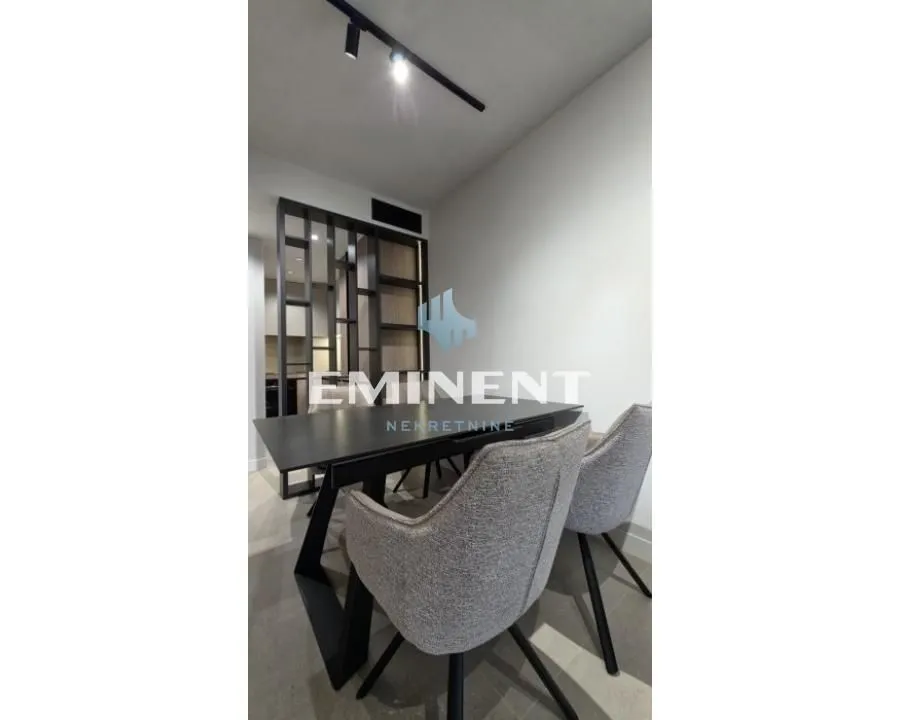Dining area with a black table and upholstered chairs next to a partition wall.