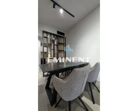 Dining area with a black table and upholstered chairs next to a partition wall. - image 4