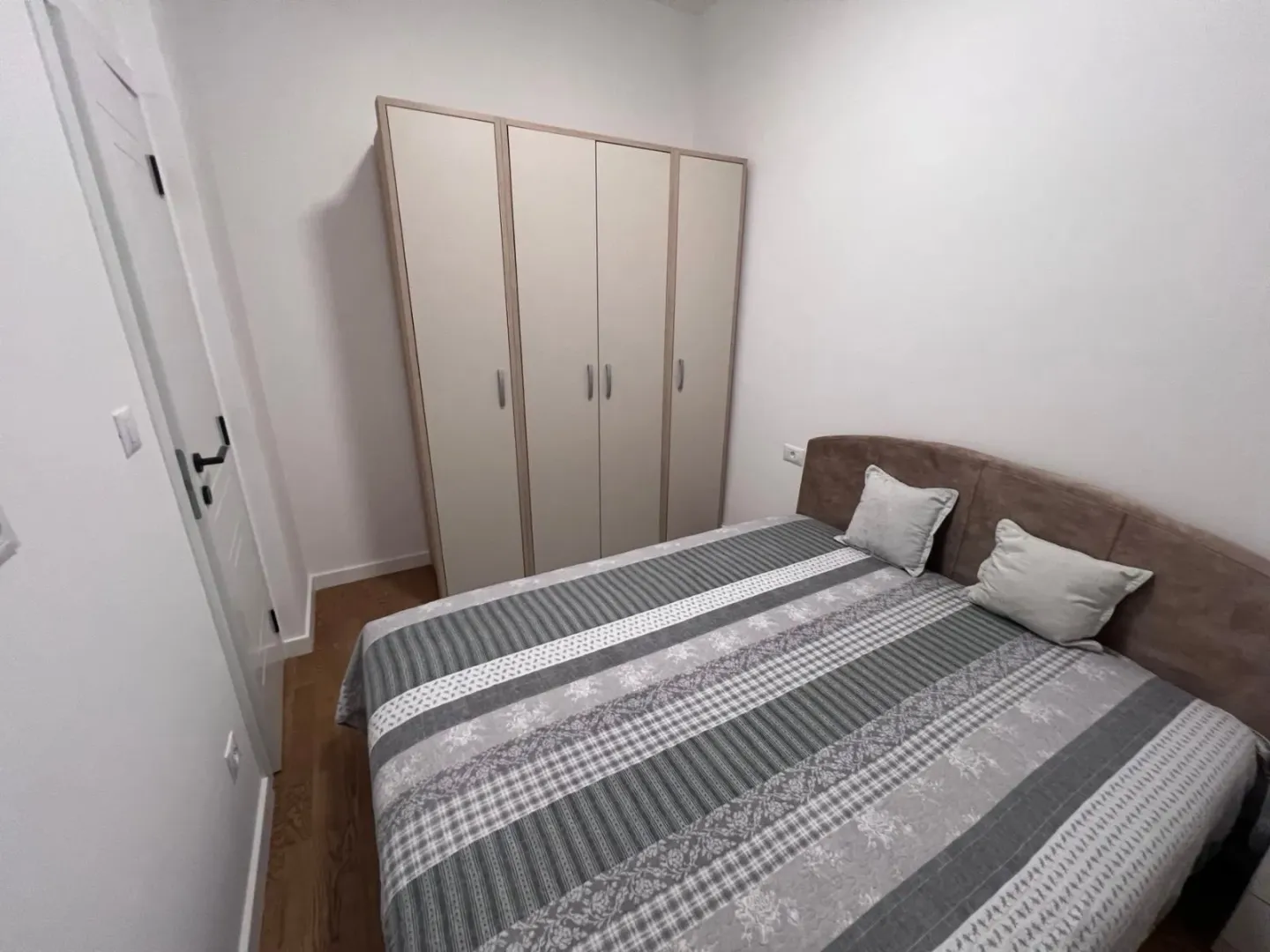 Namještena spavaća soba sa bračnim krevetom i garderoberom.