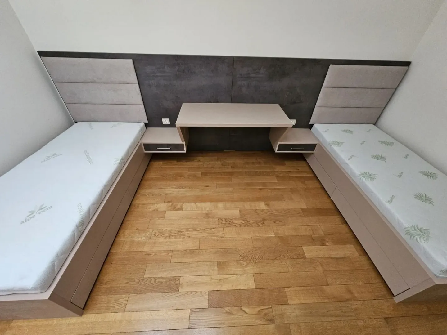 Spavaća soba sa dva singl kreveta i radnim stolom.