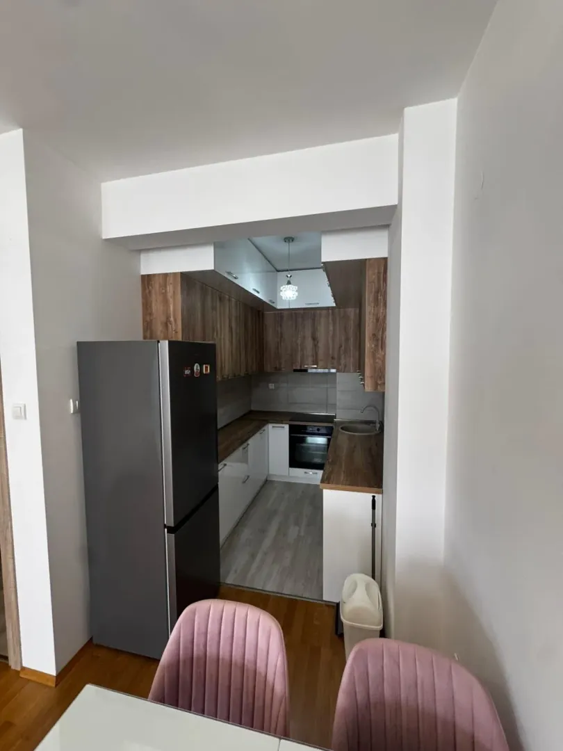 View of a modern kitchen with wooden cabinetry and a dining table in the foreground.