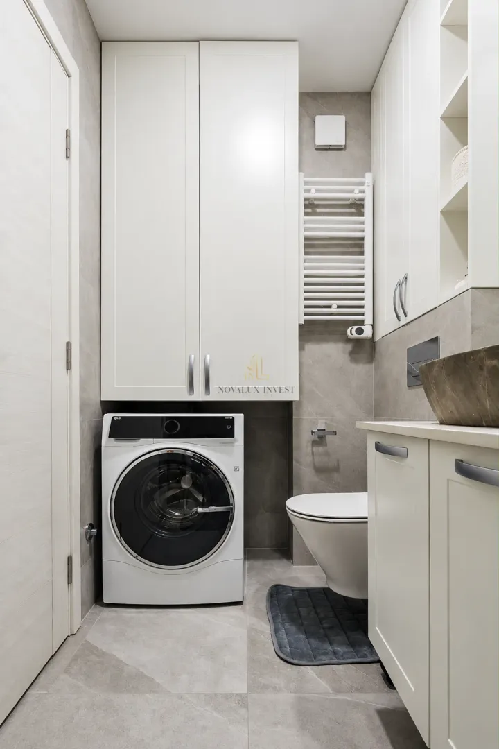 Modern bathroom equipped with a washing machine and built-in cabinetry.