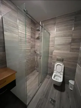 Moderno kupatilo sa tuš kabinom i pločicama u dezenu drveta. - image 13
